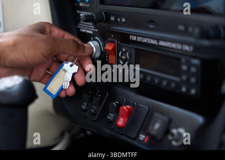 Pilot inserting key in ignition switch of aircraft cockpit panel Stockfoto