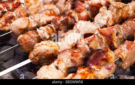 Das Fleisch wird in Nahaufnahme auf einem Gitter über Holzkohle gegrillt. Stockfoto