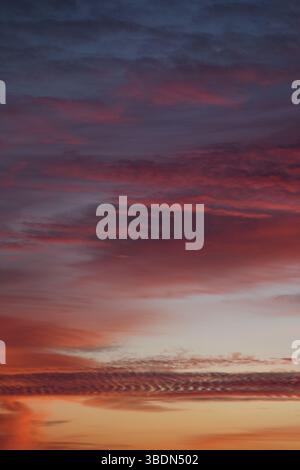 Romantischer Himmel. Violetter gelber Sonnenuntergang. Eine Vielzahl von Wolken. Universelles vertikales Foto. Das Hintergrundbild. Stockfoto