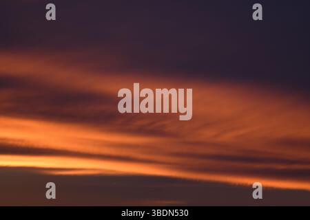 Licht bricht durch die Wolken. Universelle Fotos. Helle Wolken bei Sonnenuntergang. Rosafarbener, blauer romantischer Himmel. Das Hintergrundbild. Stockfoto
