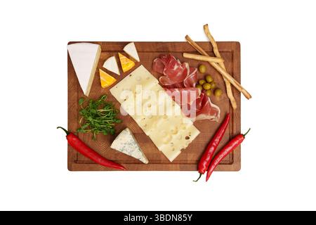 Käseplatte isoliert auf weißem Tisch. Verschiedene Käsesorten, Chili, Marmelade, Oliven, Mikrogemüse, Messer, Brotstangen. Snack. Blick von oben. Stockfoto