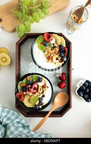 Frühstück mit griechischem Joghurt, Müsli und Obst auf weißem Holzhintergrund. Frischer Joghurt. Konzept Für Gesundes Essen. Draufsicht, Flach, Kopierbereich Stockfoto