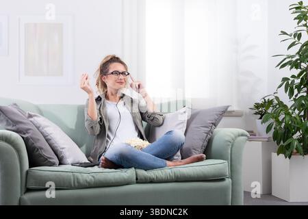 Frau mit einer intelligenten Brille, Popcorn hält sie an ihrer Brille, als ob sie mit einem virtuellen Display interagiert. Blick in den Weltraum mit digitalem und digitalem Stockfoto