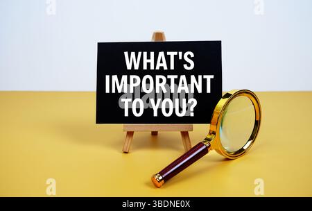 Was ist Ihnen wichtig? Text auf Papierkarte mit Lupe auf gelbem Hintergrund Stockfoto