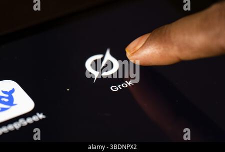In dieser Fotoabbildung tippt eine Person am 24. Mai 2025 in Neu-Delhi, Indien, Asien auf das Anwendungssymbol Grok AI auf einem Tablet-Gerät Stockfoto