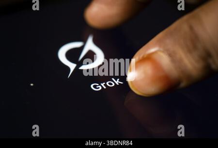 In dieser Fotoabbildung tippt eine Person am 24. Mai 2025 in Neu-Delhi, Indien, Asien auf das Anwendungssymbol Grok AI auf einem Tablet-Gerät Stockfoto