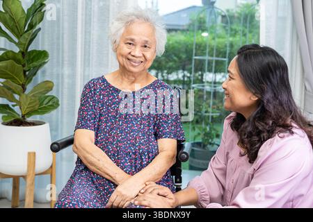 Betreuer helfen und betreuen asiatische Seniorinnen oder ältere Frauen, die zu Hause im Rollstuhl sitzen. Stockfoto
