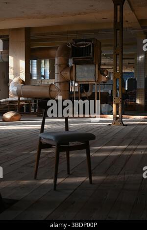 Ein leeres, verlassenes Zimmer mit einem alten Stuhl in der Mitte Stockfoto