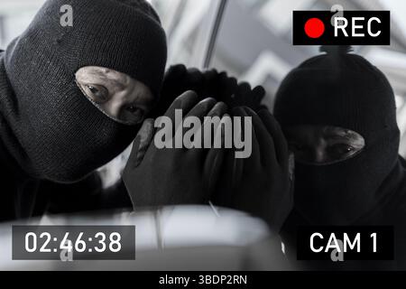 Maskierter Einbrecher in schwarzen Handschuhen, der durch das Fenster schaut, aufgezeichnet von der Überwachungskamera nachts. Konzept der Überwachung, Verbrechensverhütung, Diebstahl und Heim Stockfoto
