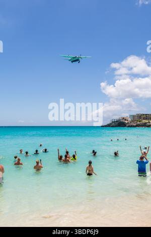 Die Schwimmer winken dem Flugzeug zu, das tief über Maho Beach fliegt, als sie den Prinzessin Juliana International Airport auf der Karibikinsel Sint M erreichen Stockfoto