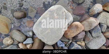 Verschiedene farbige Steine liegen auf einem Sandstrand Stockfoto