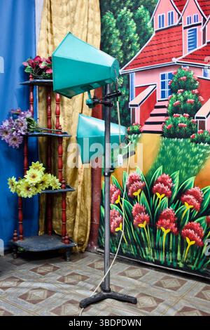 Ein Retro-Porträtstudio in Gazipur, Bangladesch, mit farbenfrohen, bemalten Kulissen und Bühnenbeleuchtung, die eine Haus- und Gartenszene simulieren. Stockfoto