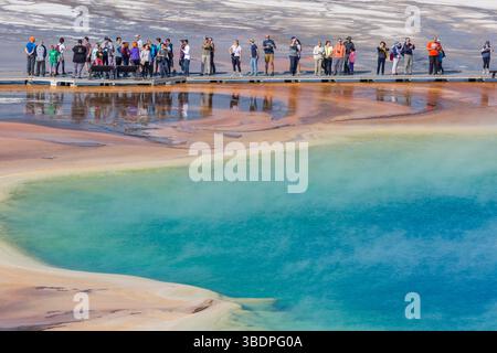 Parkbesucher auf der Aussichtsplattform können die Grand Prismatic Spring im Midway Geyser Basin des Yellowstone National Park, Wyomin, aus nächster Nähe betrachten Stockfoto