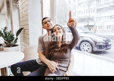 Paare genießen gemütliche Momente in einem Café, während sie an einem verschneiten Tag nach draußen zeigen Stockfoto