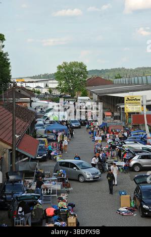 Flohmarkt in der Stadt das Foto zeigt einen Flohmarkt in einer Straße zwischen Gebäuden. Die Menschen verkaufen verschiedene Gegenstände wie Kleidung, Spielzeug, und Stockfoto