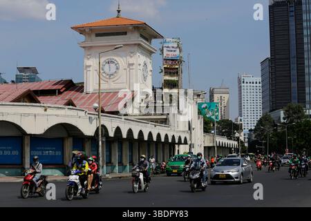 Ho Chi Minh, Vietnam - 23. Dezember 2022: Motorradfahrer fahren am berühmten Ben Thanh Markt in einer belebten Straße von Saigon vorbei. Stockfoto