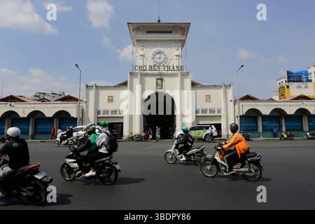 Ho Chi Minh, Vietnam - 23. Dezember 2022: Motorradfahrer fahren am berühmten Ben Thanh Markt in einer belebten Straße von Saigon vorbei. Stockfoto