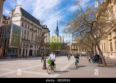 Radfahren in Paris, Frankreich. An einem schönen Frühlingstag fahren die Menschen mit dem Fahrrad vorbei an der historischen Pariser Architektur des Palais de Justice. Stockfoto