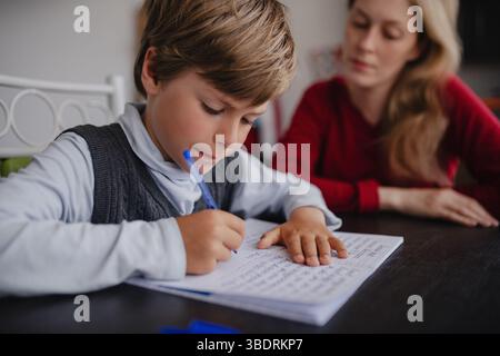Junge Schüler macht seine Hausaufgaben zu Hause mit seiner Mutter Stockfoto