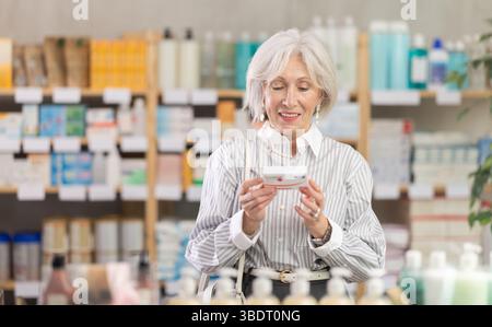 Ältere Frau in Sommerkleidung scannt den Code auf der Verpackung der Paracetamol-Pillen, um das Verfallsdatum zu überprüfen Stockfoto