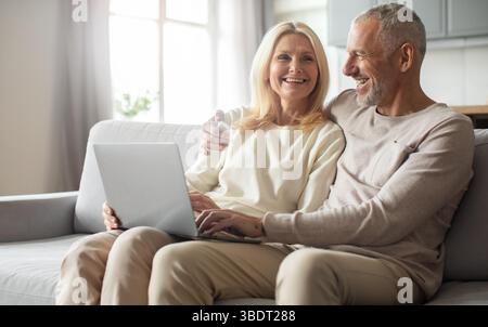 Ein Paar genießt eine schöne Zeit mit einem Laptop in seinem gemütlichen Zimmer Stockfoto