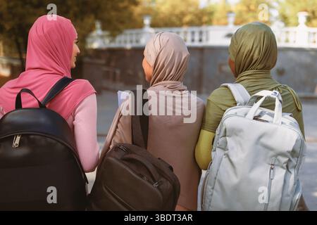 Drei Muslimische Damen Mit Rucksäcken Gehen Zurück Zur Kamera Im Freien Stockfoto