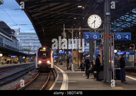 SBB Rabe 523 Elektrozug fährt am Bahnhof Lausanne (Schweiz) mit Schweizer Bahnuhr und wartenden Fahrgästen Stockfoto