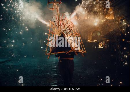Dramatisches Nachtfoto eines Mädchens, das unter einem mit Feuerwerk beleuchteten torito läuft, umgeben von Funken und Rauch während einer Feier in den Kolonialstraßen Stockfoto