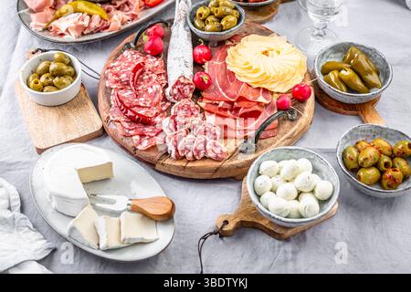 Verschiedene Vorspeisen und Antipasti-Platten auf Holztablett, Catering-Konzept mit Aufschnitt und Käse Stockfoto
