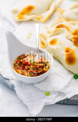 Traditionelle Empanadas mit Chimichurri-Sauce. Lateinamerikanische Küche. Stockfoto