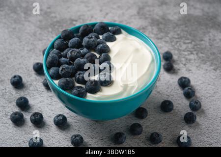 Blick von oben auf frische Heidelbeeren auf cremigem Joghurt in einer blauen Schüssel Stockfoto