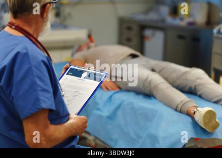 Arzt, der auf dem Untersuchungstisch liegende Krankenakte untersucht Stockfoto