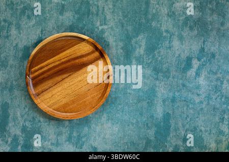 Minimalistischer runder Holzteller auf einer weichen, blauen Marmor-Textur. Perfekt für Lebensmittelfotos, das Servieren von Mockups oder elegante Küchendesign-Hintergründe, Top Stockfoto