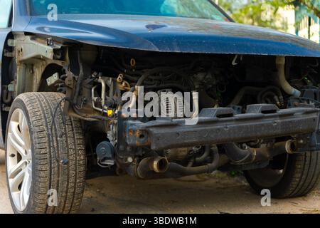 Vorderansicht eines beschädigten Fahrzeugs mit fehlendem Stoßfänger und freiliegenden Motorkomponenten, was einen umfangreichen Reparaturbedarf zeigt. Stockfoto
