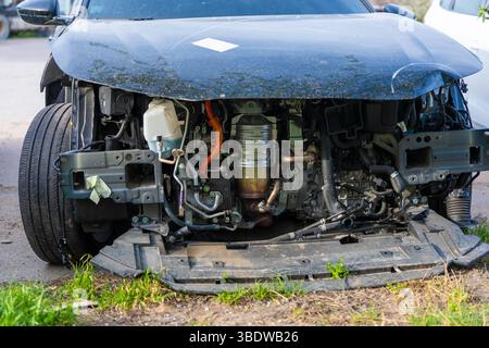 Nahaufnahme eines modernen Fahrzeugs mit entferntem vorderen Stoßfänger, wobei komplexe Motorkomponenten, Verkabelung und interne Systeme freigelegt werden. Stockfoto