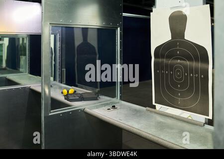Tablett auf dem öffentlichen Schießstand mit mehreren Zielsilhouetten, die hängen und einige Ausrüstung auf dem Tablett liegen. Saubere, gut beleuchtete Umgebung, geeignet für das Üben von Schusskunst Stockfoto