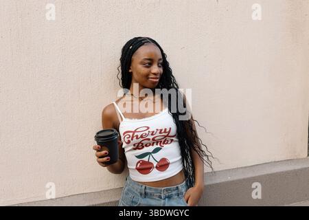 Schöne junge schwarze Frau mit Kaffee in der Hand Stockfoto