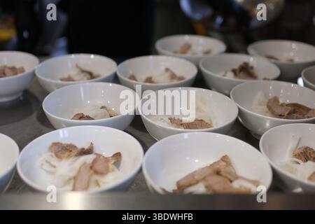 Viele weiße Suppenschalen im Buffet Reisnudeln und Fleischstücke warten darauf, mit Brühe gefüllt zu werden Stockfoto