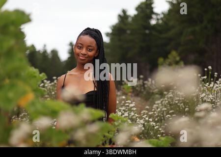 Eine junge Frau, die auf einem Blumenfeld steht Stockfoto