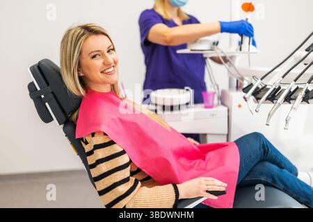 Glückliche junge Frau in der modernen Zahnklinik. Sie schaut in die Kamera und lächelt. Stockfoto