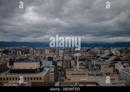 Weitwinkelblick auf Kyoto mit einer Tempelpagode im Vordergrund, Dächern der Stadt und sanften Bergen im Hintergrund bei leichtem Tageslicht Stockfoto