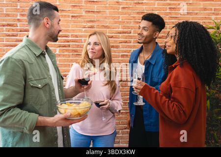 Multiethnische Gruppe von Freunden, die Abendessen und Unterhaltung am Heimtisch genießen Stockfoto