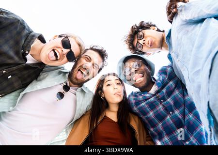 Multirassische Gruppe junger Freunde, die ihre Zunge ausstrecken und Spaß haben. Spontane Freude, Einheit und Freiheit draußen. Stockfoto