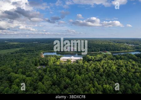 Ein üppig grüner Wald mit einem großen Gebäude in der Mitte. Der Himmel ist bewölkt und die Sonne scheint durch die Wolken. Richmond, USA Stockfoto