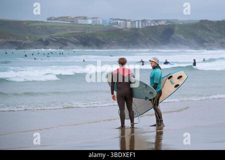 Ein Surflehrer der Escape Surf School unterhält sich mit einem anderen Surfer am Towan Beach in Newquay in Cornwall, Großbritannien. Stockfoto