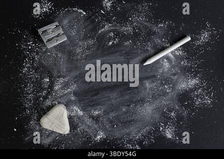 Weiße Kreidespäne und -Flecken auf schwarzem Karton, mit weißem Buntstift, Radiergummi Stockfoto
