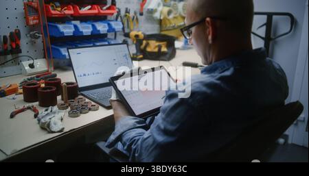 Mitarbeiter überwachen Echtzeitbestände, Börsen von Marktdiagrammen mit Tablet-Computer und Laptop. Mann, der Kryptowährungen während des Arbeitstages in Workshop investiert und Job mit Online-Handel kombiniert. Stockfoto