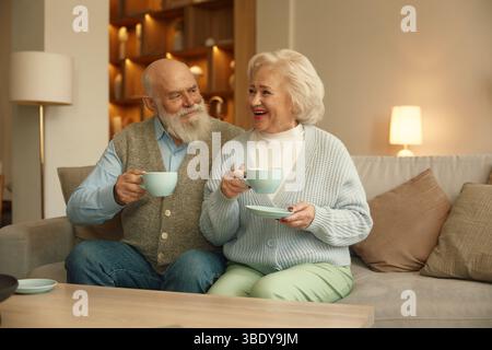Ein älterer Mann und eine Frau heirateten ein Paar, das zusammen Kaffee im Wohnzimmer trank Stockfoto