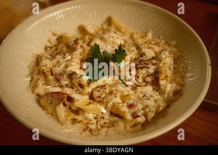 Cremig gebackene Penne mit Käsesoße, Kräutern und Petersilie Stockfoto