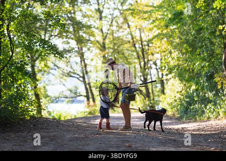 Ein reifer Vater mit einem kleinen Sohn und einem Hund, der angeln geht. Stockfoto